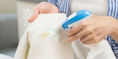 Žena čistí bílý textil odstraňovačem skvrn