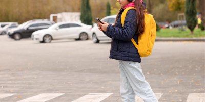Dívka s mobilem na přechodu pro chodce