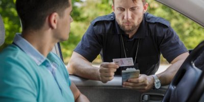 Policista provádí kontrolu řidičských průkazů