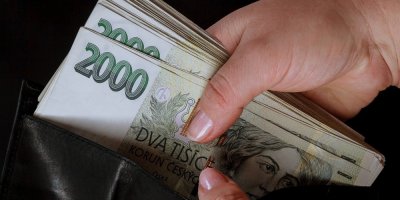 Ženské ruce držící peněženku plnou dvoutisícových bankovek
