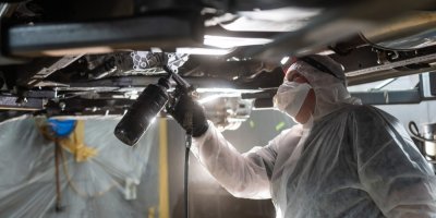 Automechanik aplikuje antikorozní sprej na podvozek auta