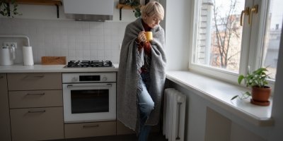 Žena stojící v kuchyni u radiátoru