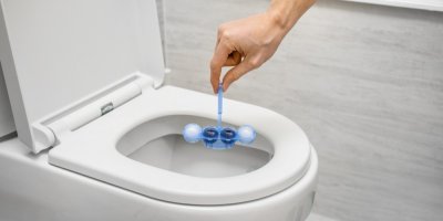 Muž drží WC blok nad toaletní mísou