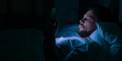 Muž se v noci dívá do mobilu
