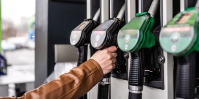 Ruka držící čerpací pistoli na čerpací stanici