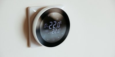 Detail moderního inteligentního termostatu na zdi s 22 stupni Celsia