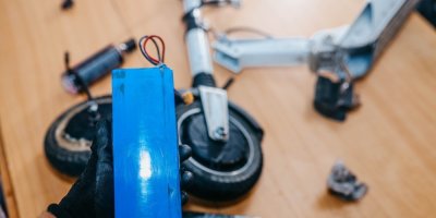 Servisní technik drží vyjmutou baterii elektrokoloběžky při opravě v dílně