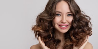 Usměvavá žena s hnědými, vlnitými vlasy