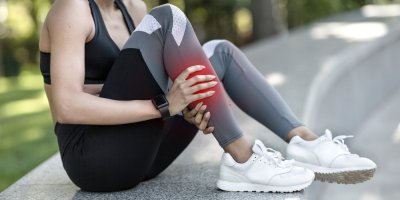 Žena ve sportovním oblečení v parku trpí bolestí nohy