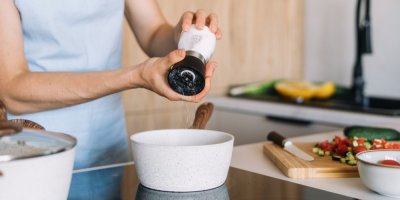 Žena používá ruční mlýnek na sůl při přípravě jídla