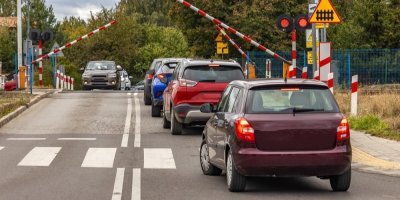 Auta stojící před uzavřeným železničním přejezdem
