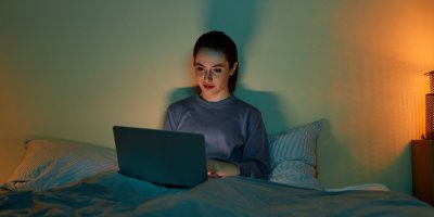 Žena se dívá v posteli na seriál na notebooku