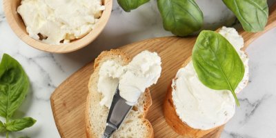 Bagetka namazaná čerstvým sýrem a ozdobená lístkem bazalky