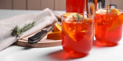 Dvě skleničky a Aperolem na stole, ozdobené snítkou rozmarýnu a plátky pomerančů