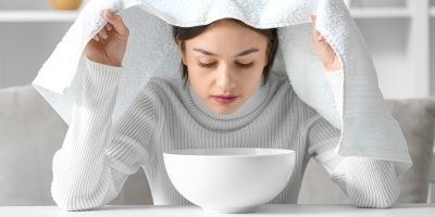 Žena inhalující páru z misky