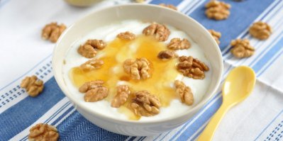 Řecký jogurt s medem a vlašskými ořechy na modro-bílém ubrusu