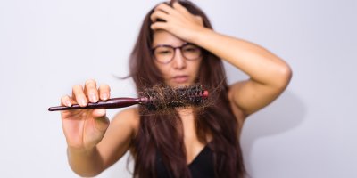 Žena před zrcadlem překvapená z množství vyčesaných vlasů 