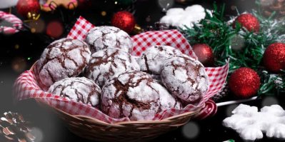 Čokoládové sušenky crinkles obalené v cukru v ošatce, v pozadí vánoční dekorace