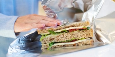 Žena balí sendvič do alobalu