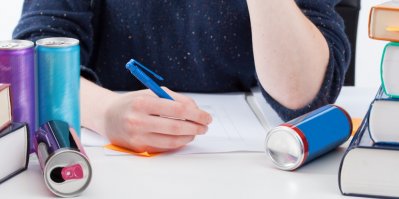 Student učící se do školy, vedle něj ležící plechovky od energy drinků
