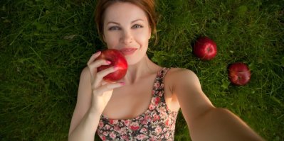 Žena jí jablko a zároveň se u toho fotí