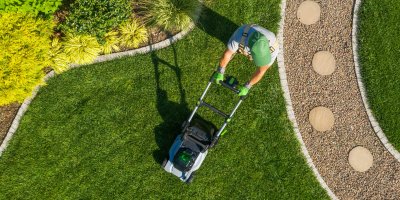 Muž seká trávník sekačkou na zahradě