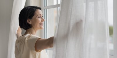 Žena v bílé košili roztahuje bílé záclony