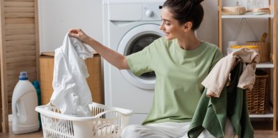 Žena přebírá různé věci v koši na praní