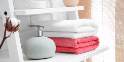 Poskládané ručníky a dávkovač na tekuté mýdlo v koupelně