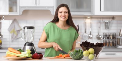 Usmívající se žena krájí zeleninu v kuchyni