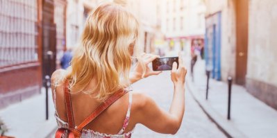 Žena si mobilním telefonem fotí ulici