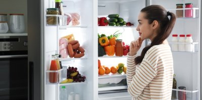 Žena se dívá do lednice plné jídla