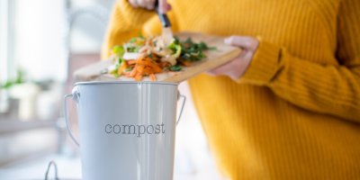 Žena vyhazuje zbytky zeleniny do domácího kompostéru