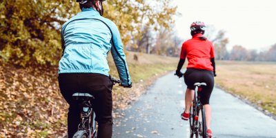 Cyklisté jedou po mokré cyklostezce v podzimním počasí