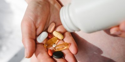 Různé druhy vitamínů a pilulek na dlani