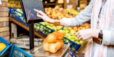 Žena váží jablka na váze v supermarketu 