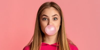 Žena nafukuje bublinu ze žvýkačky