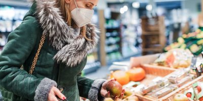 Žena s respirátorem vybírá ovoce v supermarketu 