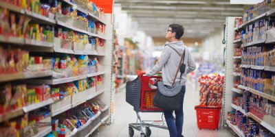 Žena před sebou tlačí nákupní vozík v supermarketu a rozhlíží se