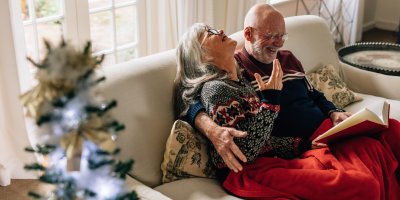 Manželé seniorského věku si předávají vánoční dárky a smějí se
