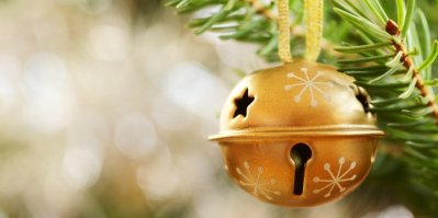 Zlatá rolnička zavěšená na červené stužce na vánočním stromku