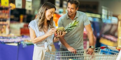 Mladá žena nakupuje v supermarketu a čichá k rajčeti