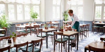 Muž připravuje v restauraci stoly 