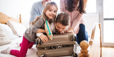 Mladá rodina balí kufr v ložnici