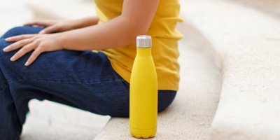 Žena sedí na schodech a vedle má žlutou lahev
