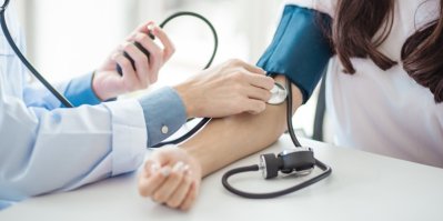 Doktorka měří pacientce krevní tlak digitálním tlakoměrem