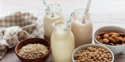Trojice sklenic rostlinných mlék a suroviny, ze kterých se vyrábí