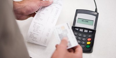 Muž kontroluje účtenku u platebního terminálu