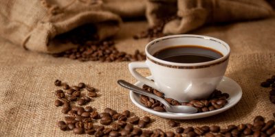 Šálek silné, černé kávy a kávová zrna