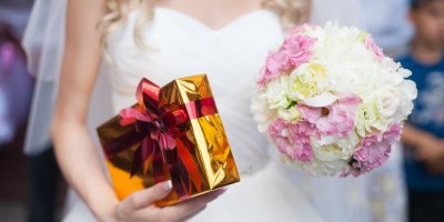 Nevěsta drží v jedné ruce kytici a v druhé zabalený dárek